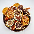 Aromatic dried citrus slices, cinnamon sticks, star anise in a rustic bowl.