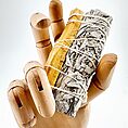 Wooden hand model holding sage and palo santo for spiritual cleansing and wellness.