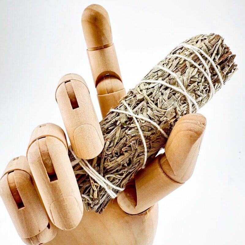 Smudge Stick Wooden mannequin hand holding dried sage bundle, contrasting textures, natural artistry.