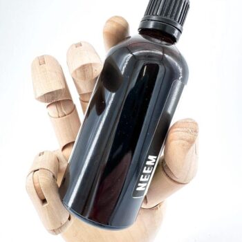 Wooden hand holding neem oil bottle against a white background for natural product advertisement.