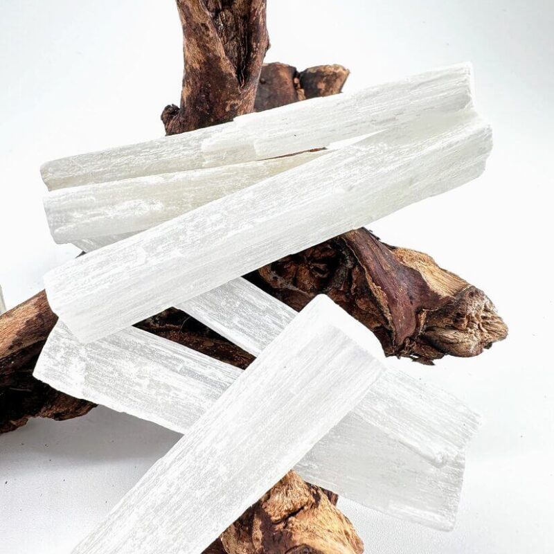 Natural Raw Selenite Crystal Wand Selenite crystals on driftwood showcasing natural textures and contrasts in light and shadow.