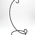Minimalist black metal wire stand with elegant curved design for displaying decorative items.