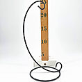 Elegant black metal stand with hook, beside wooden measuring stick on white background.