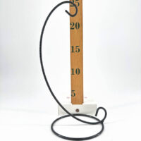Elegant black metal stand with hook, beside wooden measuring stick on white background.