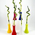 Vibrant modern vases with spiralling bamboo stalks on a minimalist white background.