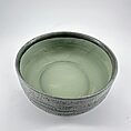Artisan bowl in muted green with textured exterior and glossy interior, perfect for decor and use.