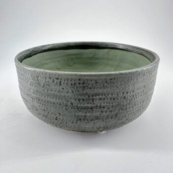 Elegant gray ceramic bowl with textured exterior and soft green interior glaze, perfect for decor.