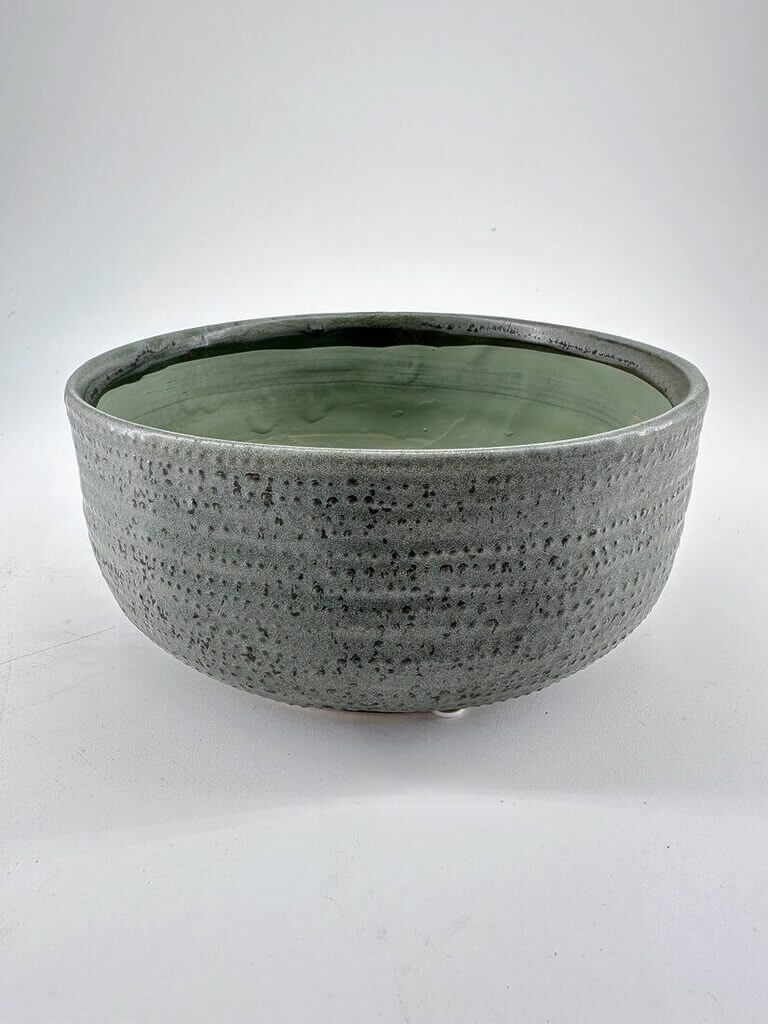 Elegant gray ceramic bowl with textured exterior and soft green interior glaze, perfect for decor.