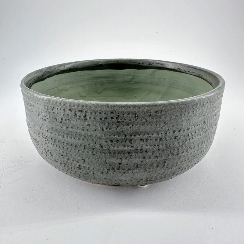 Elegant gray ceramic bowl with textured exterior and soft green interior glaze, perfect for decor.