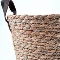 Handwoven basket made from natural fibers with leather handles, showcasing artisanal craftsmanship and style.