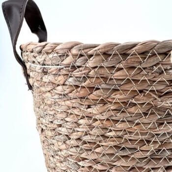 Handwoven basket made from natural fibers with leather handles, showcasing artisanal craftsmanship and style.