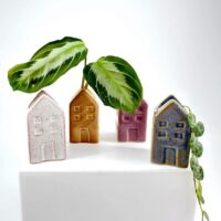 Charming ceramic house planters with plants, adding colour and texture to minimalist decor.