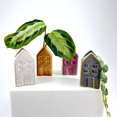 Charming ceramic house planters with plants, adding colour and texture to minimalist decor.