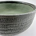 Artisan ceramic bowl with textured grey exterior and glossy green interior, perfect for display.