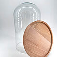Elegant glass cloche with wooden base, perfect for showcasing food or decorative items.