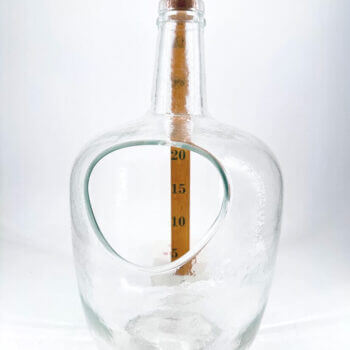 Artistic glass measuring bottle with cork, ergonomic design, and bold scale for precision.