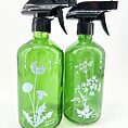 Green glass spray bottles featuring botanical illustrations for eco-friendly gardening and cleaning solutions.