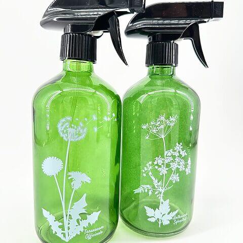 Green glass spray bottles featuring botanical illustrations for eco-friendly gardening and cleaning solutions.