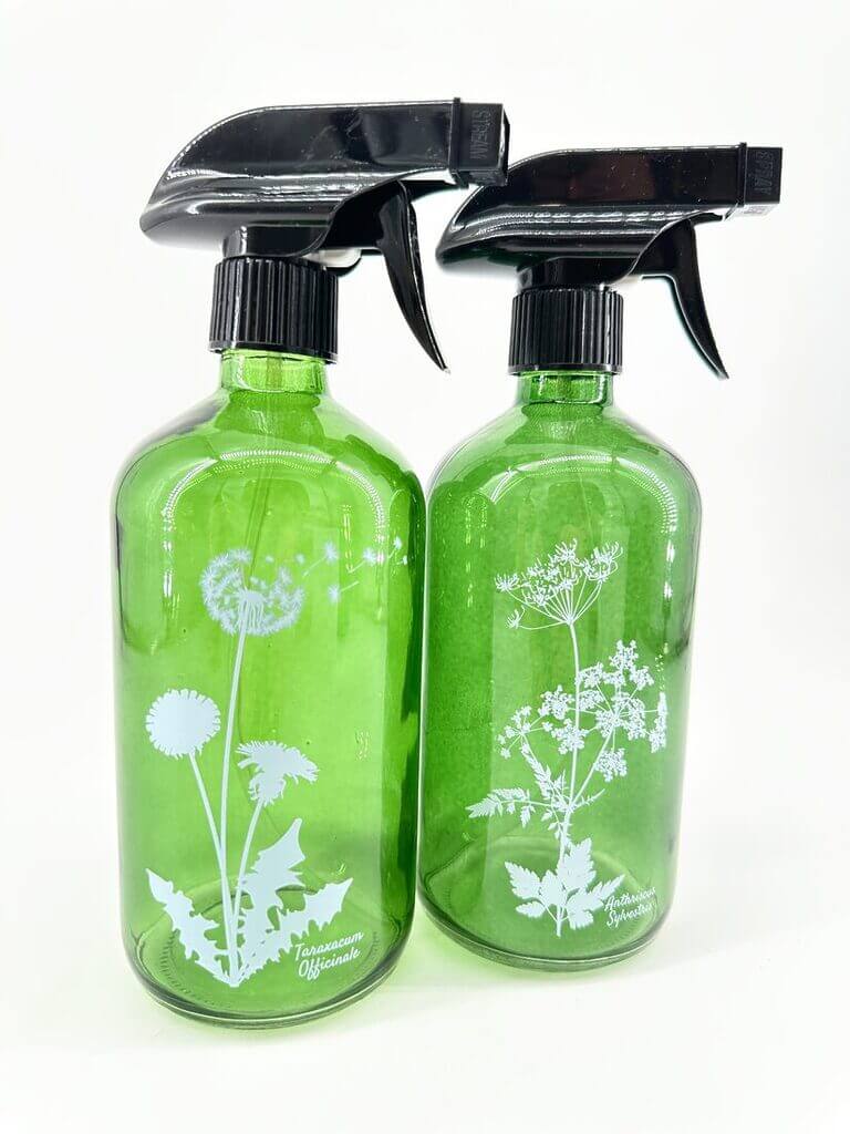 Green glass spray bottles featuring botanical illustrations for eco-friendly gardening and cleaning solutions.
