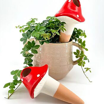 Charming mushroom figurines and lush greenery in a decorative ceramic pot create a whimsical display.