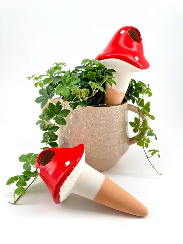 Charming mushroom figurines and lush greenery in a decorative ceramic pot create a whimsical display.