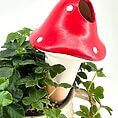 Whimsical red mushroom ornament in a charming plant pot, perfect for home décor.