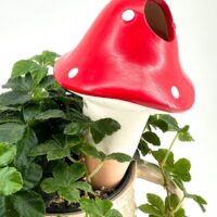 Whimsical red mushroom ornament in a charming plant pot, perfect for home décor.