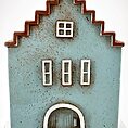 Charming miniature blue house with rustic design, zigzag roof, and white-framed windows.
