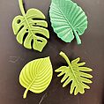 Vibrant green silicone leaves on black background, showcasing diverse shapes and textures.