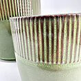 Contemporary ceramic planters with green-red glaze, ribbed texture, showcasing modern craftsmanship.