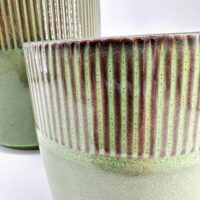 Contemporary ceramic planters with green-red glaze, ribbed texture, showcasing modern craftsmanship.