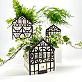 Charming house-shaped planters with lush green plants, showcasing European architectural influence.