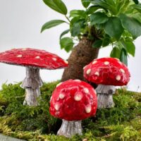 Enchanting red mushrooms on green moss in a whimsical, miniature forest scene.