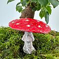 Vivid red fairy-tale mushroom on green moss with indoor plant background.