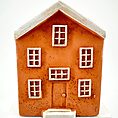 Miniature rustic orange house model with textured exterior and white roof on neutral background.