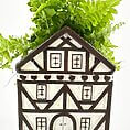 Charming half-timbered house planter with vibrant green ferns for cosy home decor.