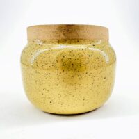Glossy yellow ceramic jar with cork lid, speckled texture, modern decor.