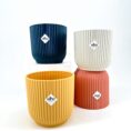 Eco-friendly elho ribbed decorative plant pots in navy, creamy white, mustard yellow, and coral.