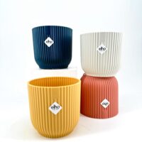 Eco-friendly elho ribbed decorative plant pots in navy, creamy white, mustard yellow, and coral.