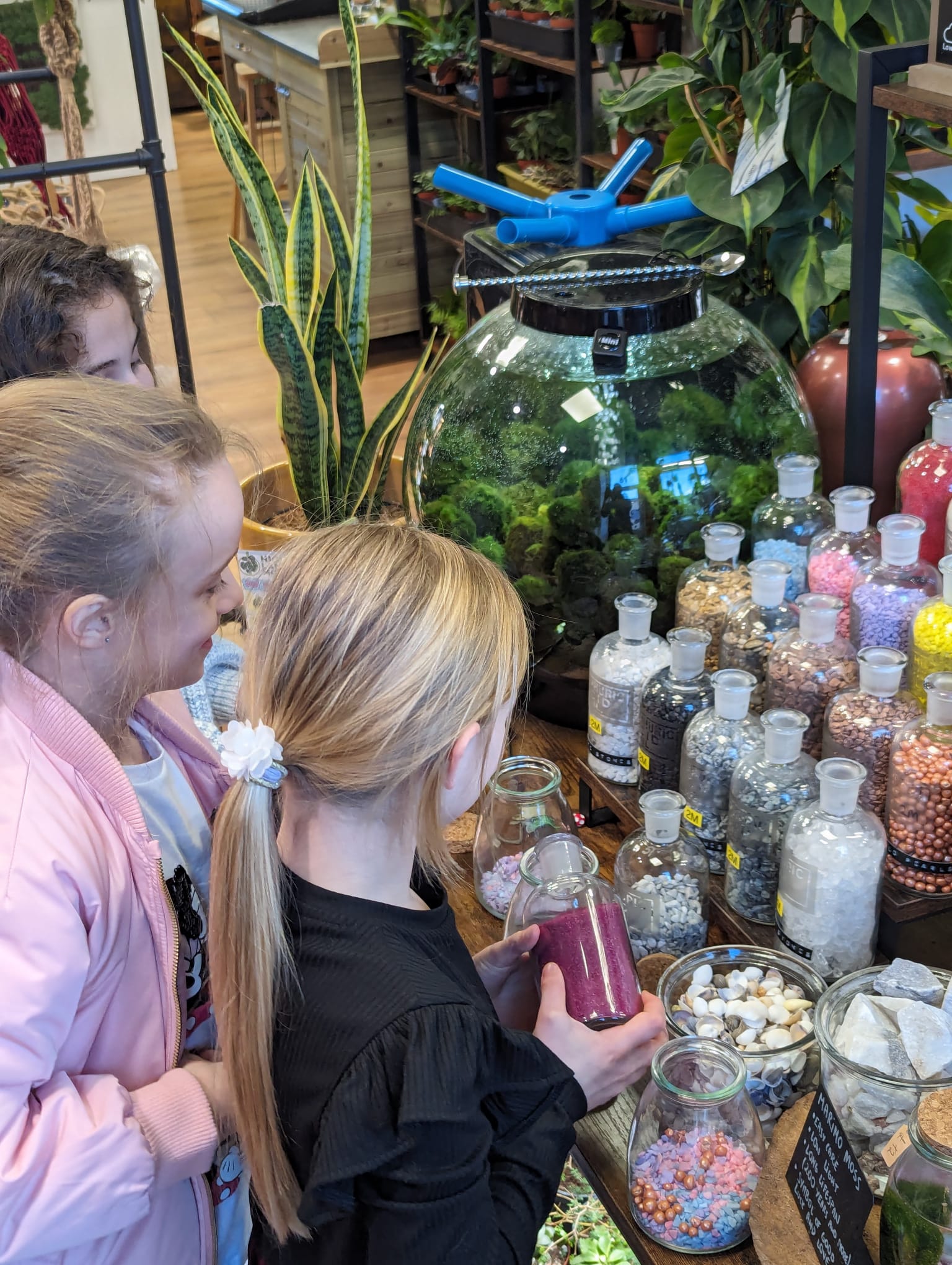 Girls crafting with colourful materials in plant shop workshop.