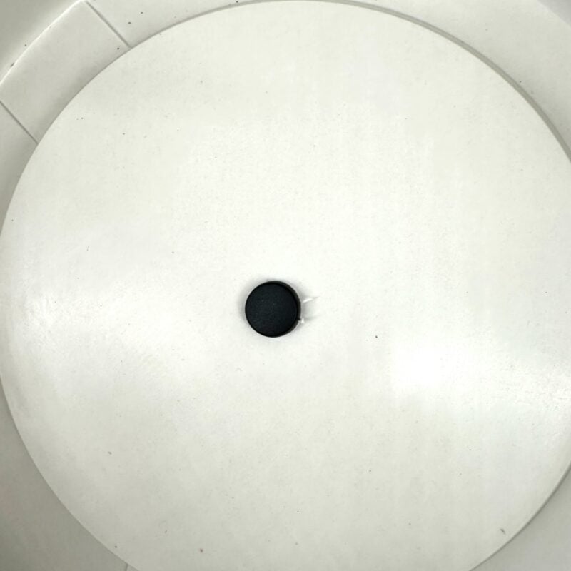 Minimalist Elegance: White Surface with Black Dot Minimalist white surface with black dot, red wire; potential electronic device component.