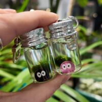 Pair of Mini Marimo Moss keyrings featuring soot spirit style decorations in black and pink.